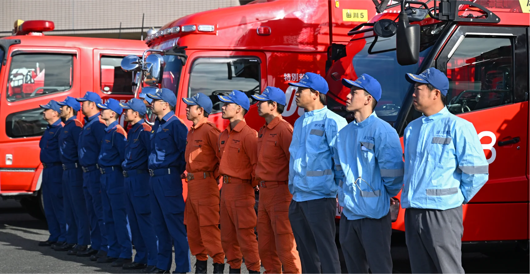 消防本部で働く人達が消防車の前で横一列に整列している様子